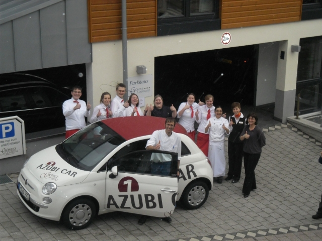 Deutsche-Politik-News.de | Gregorio Molina Reyes (vorne), strahlender „Azubi des Monats“ des Gbel’s Landhotel Willingen mit seinem neuen „AZUBI CAR“ und seinen begeisterten Kollegen sowie Hotelchefin Stephanie Gbel (ganz rechts)