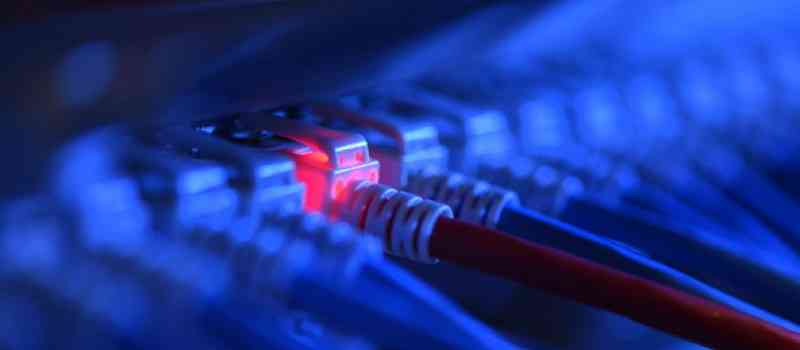 Ein Netzwerkkabelstecker leuchtet in einer Netzwerkzentrale rot.